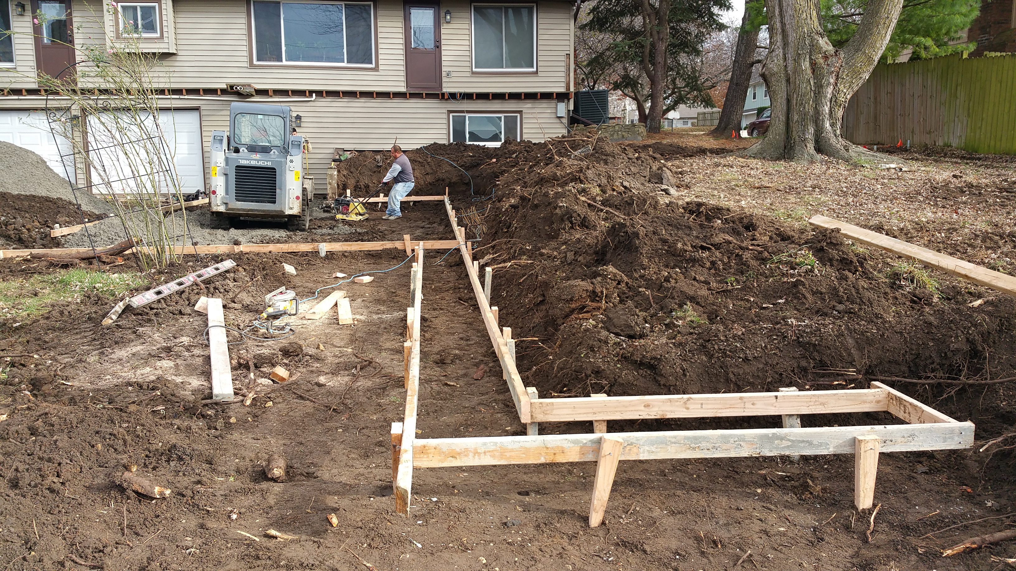 Wooden framework set up for concrete foundation near a house.