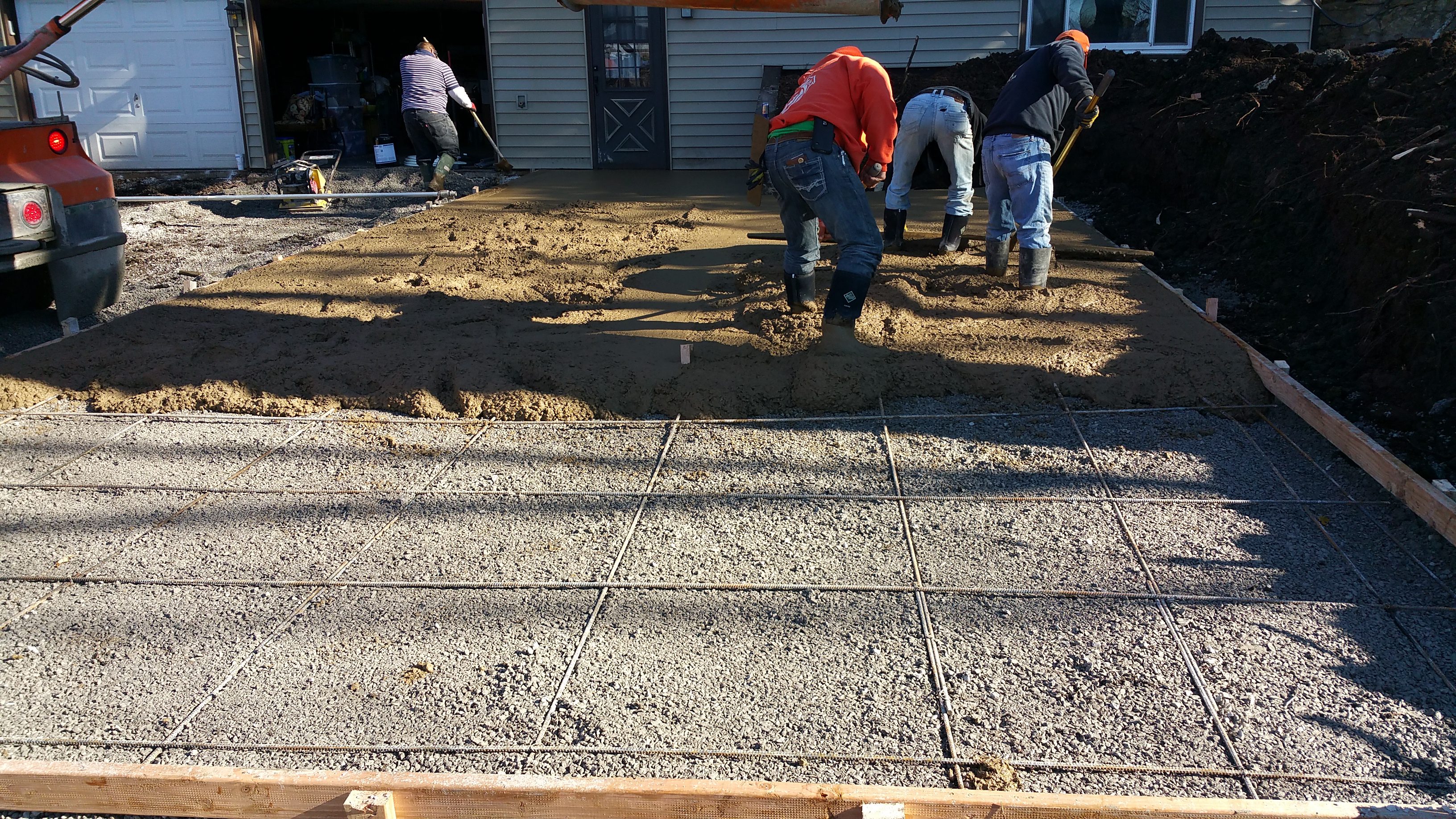 Workers preparing a concrete slab foundation with rebar reinforcement.