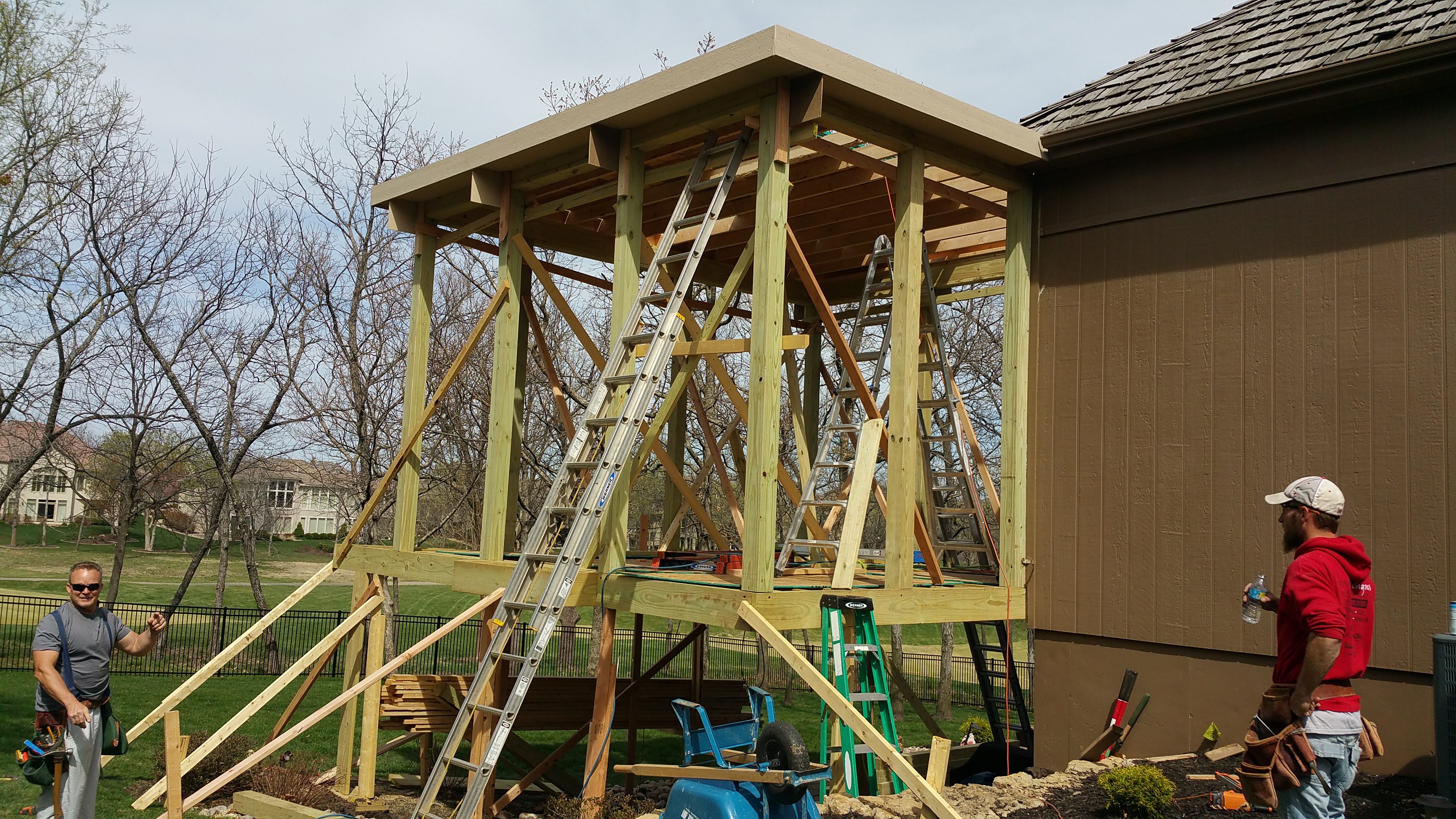 Wooden structure under construction next to a house.
