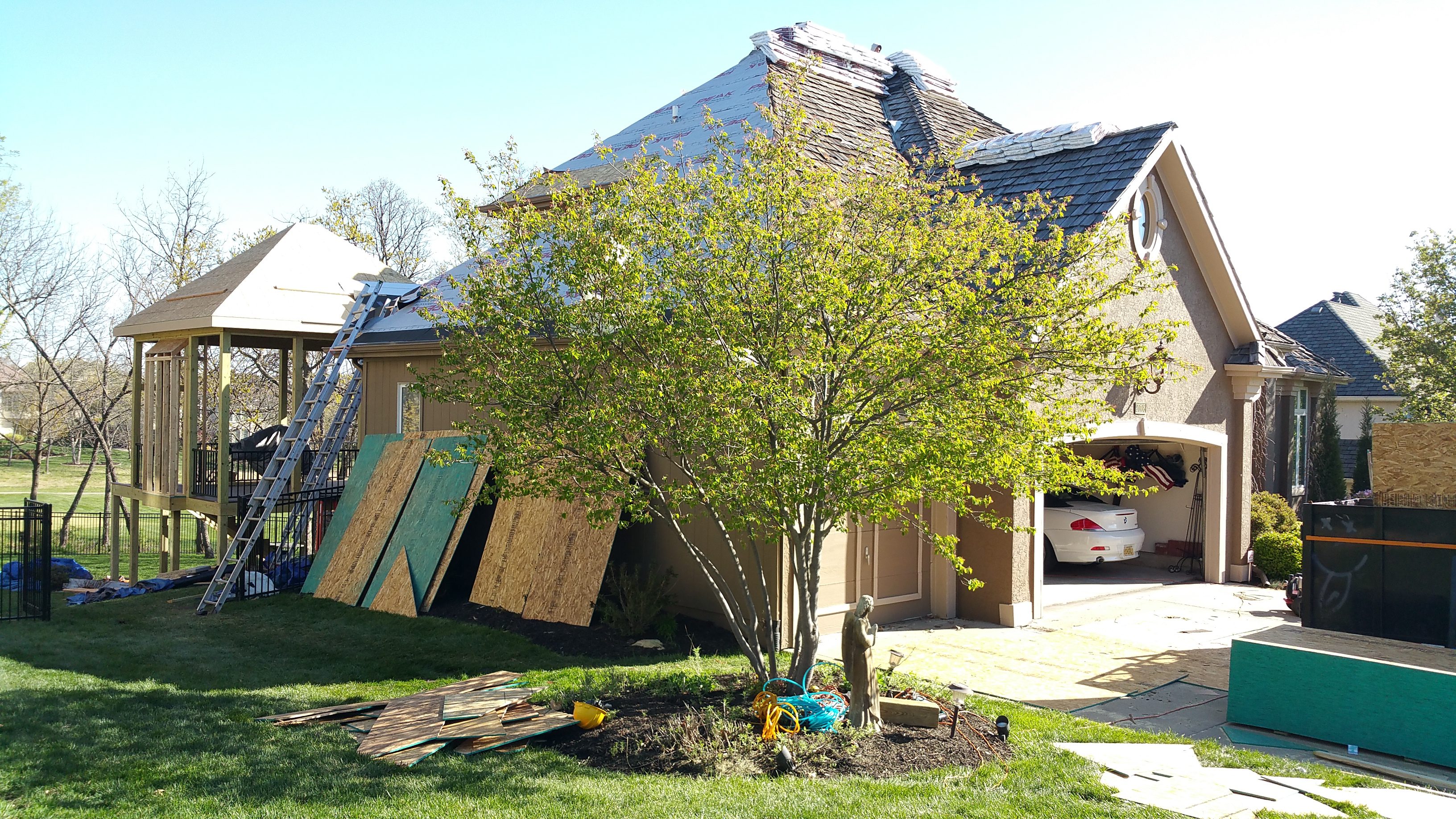 A tree in front of a house with boarded-up windows and doors.