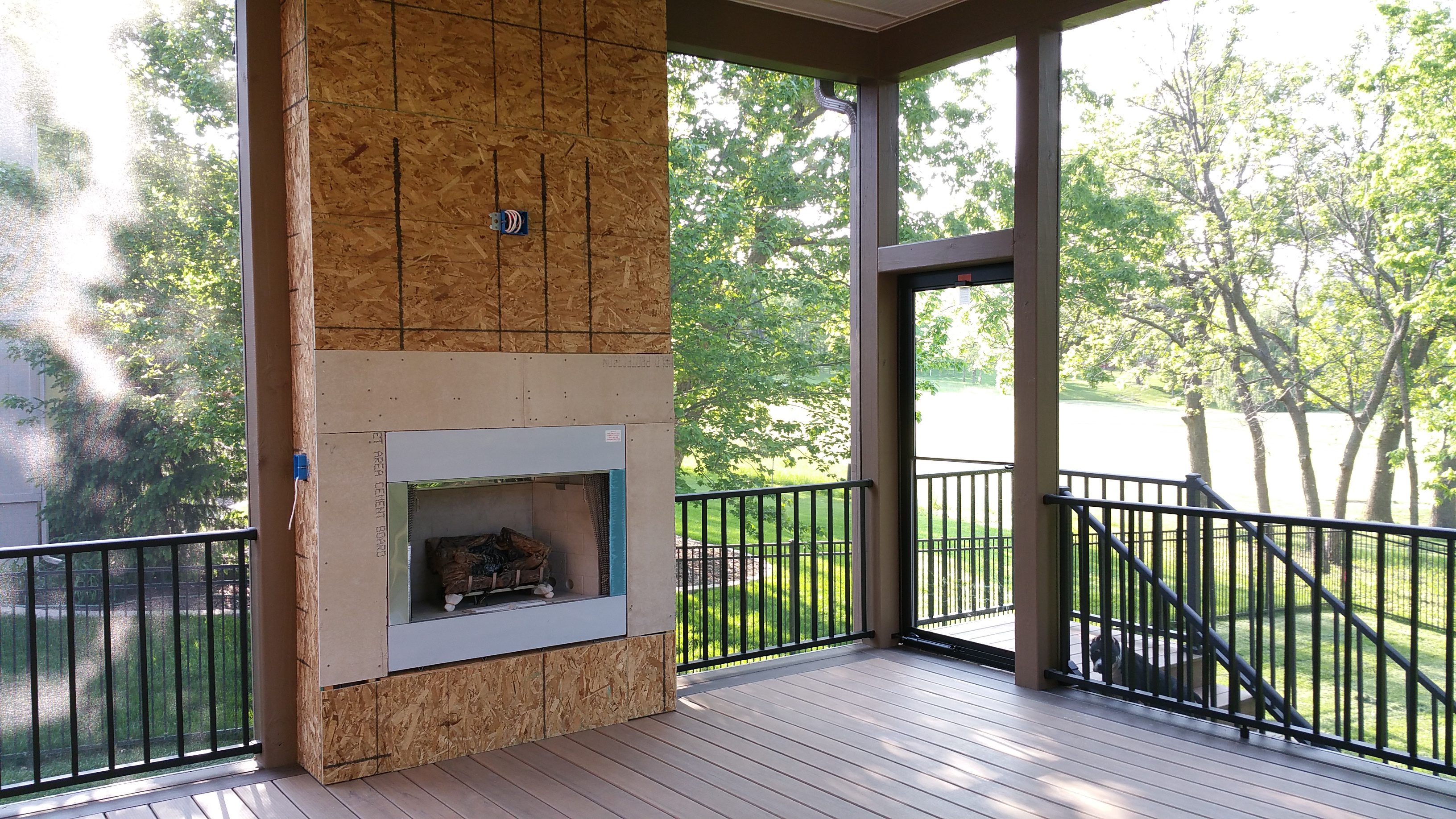 Cozy screened porch with fireplace and scenic outdoor view.