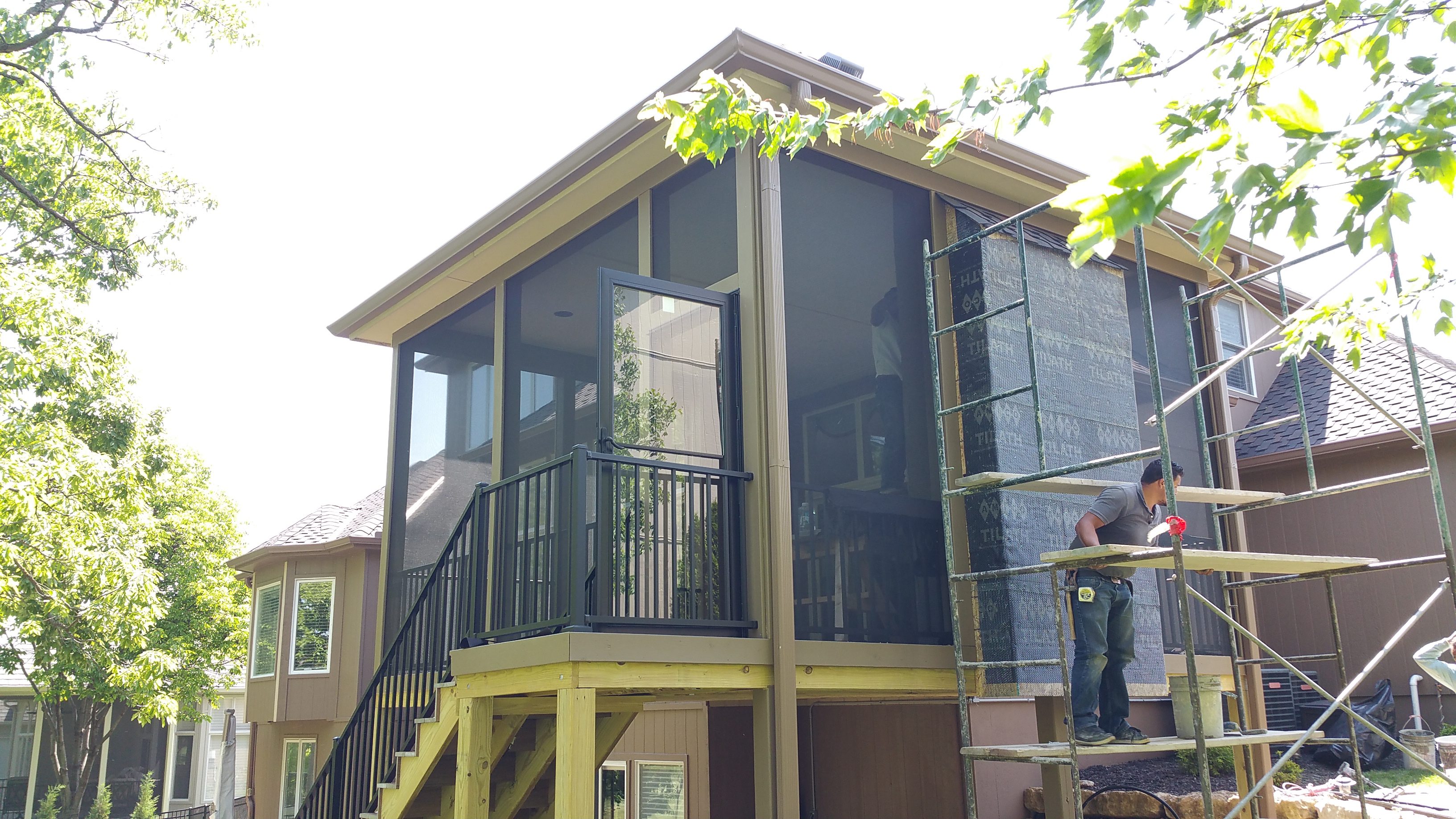Screened porch with black railings and stone wall exterior.