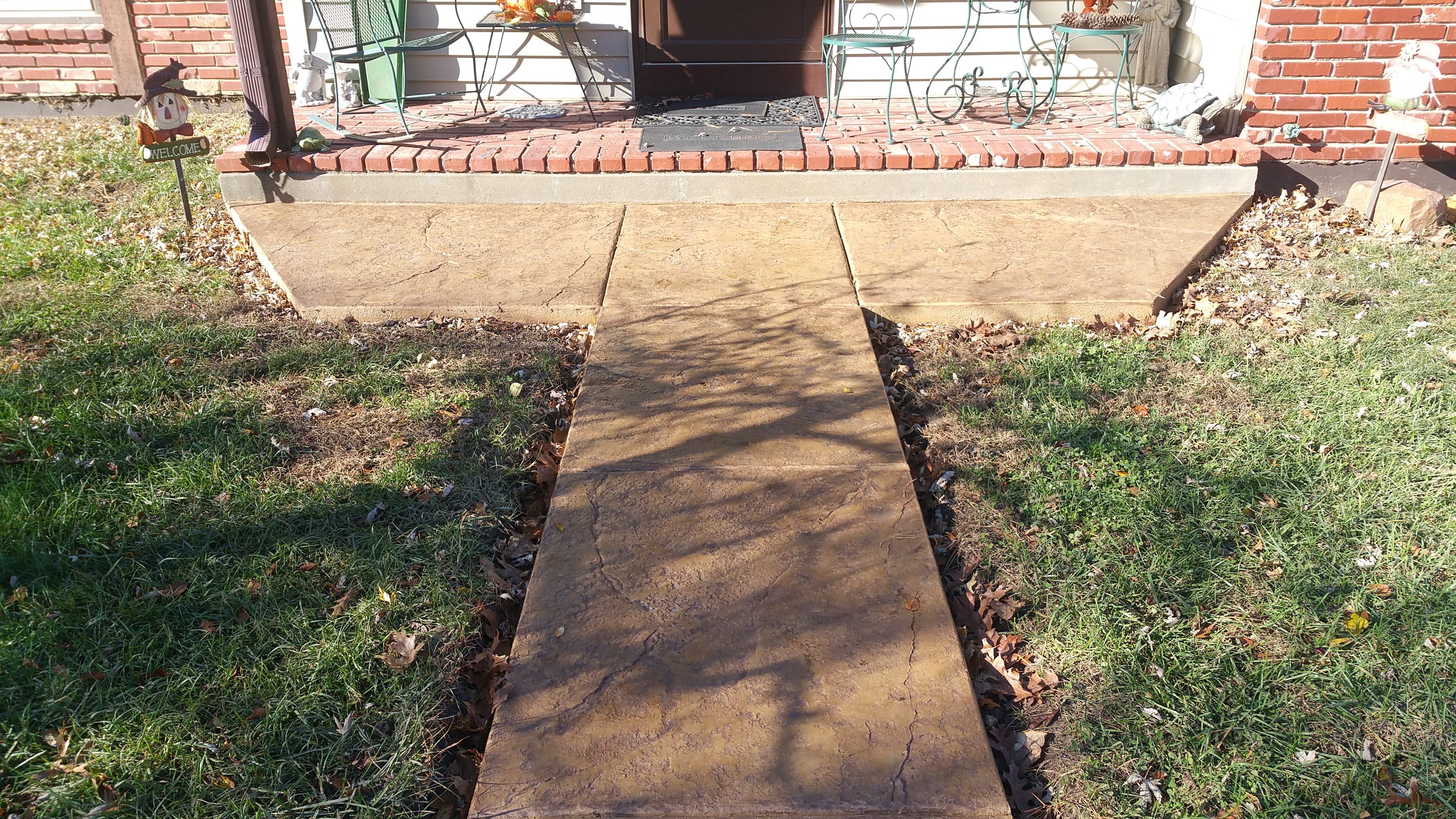 A newly poured concrete sidewalk leading to a house entrance.
