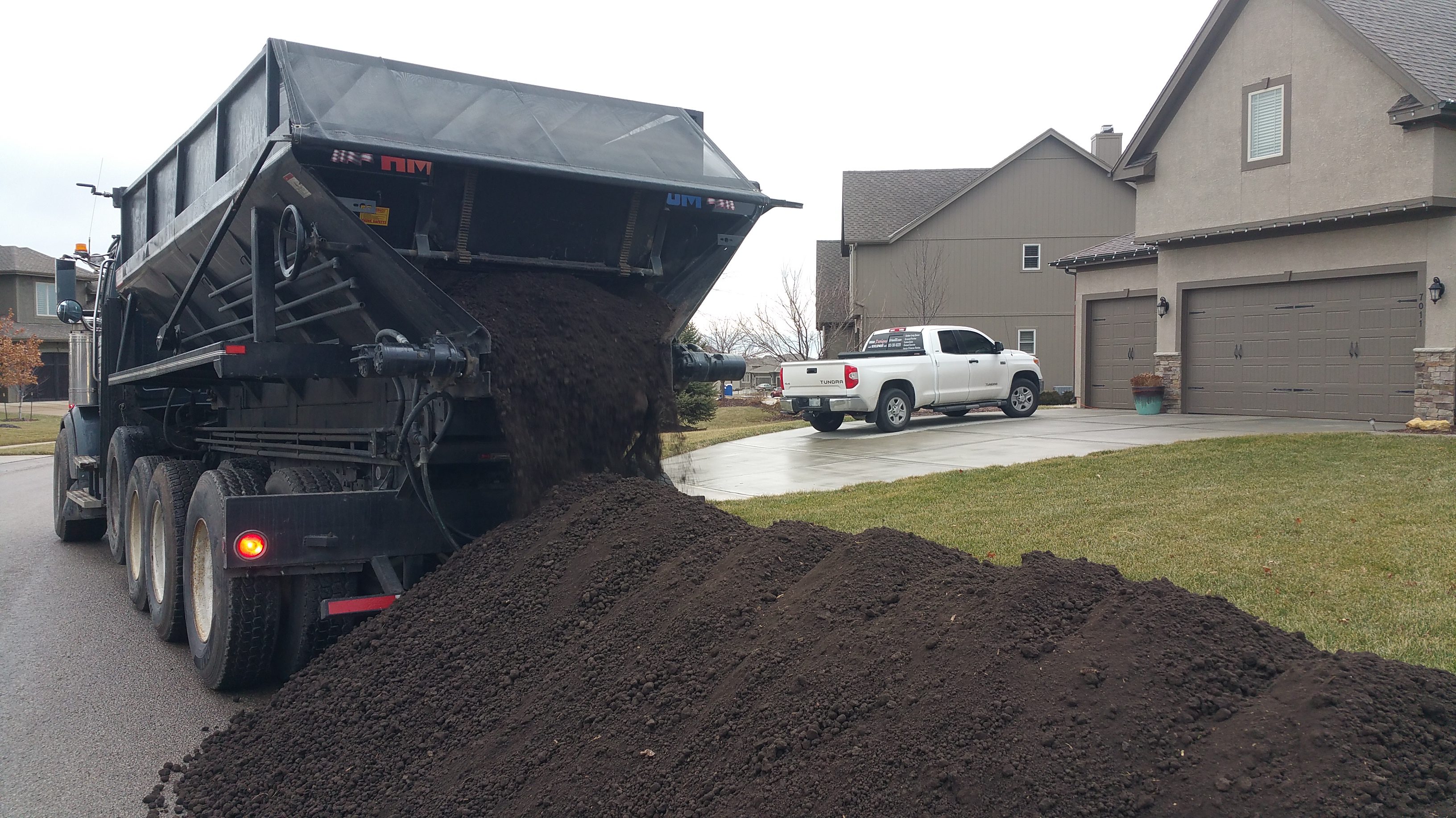 Large machine dumping soil in a residential area.