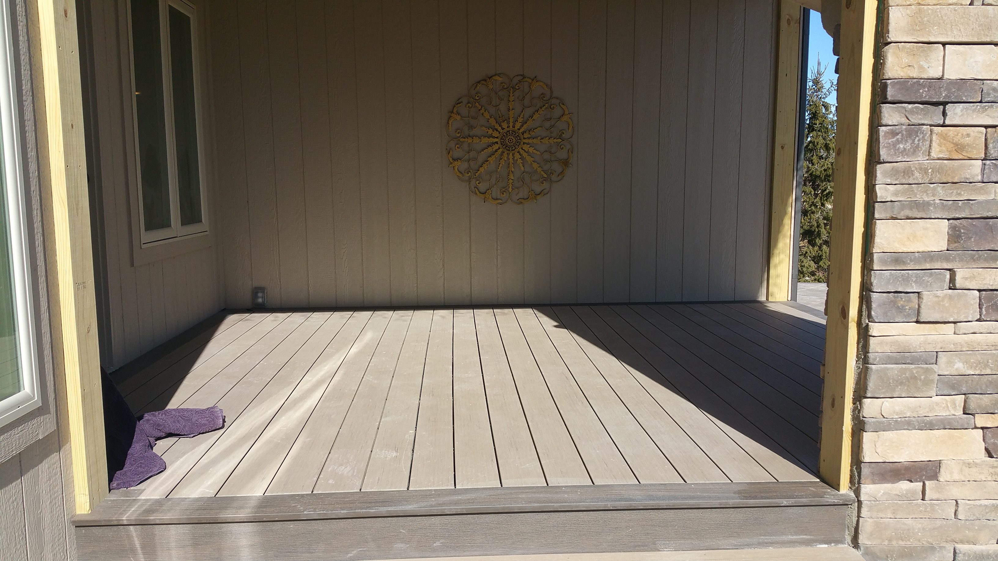 Empty wooden deck with a textured wall and decorative circular art.
