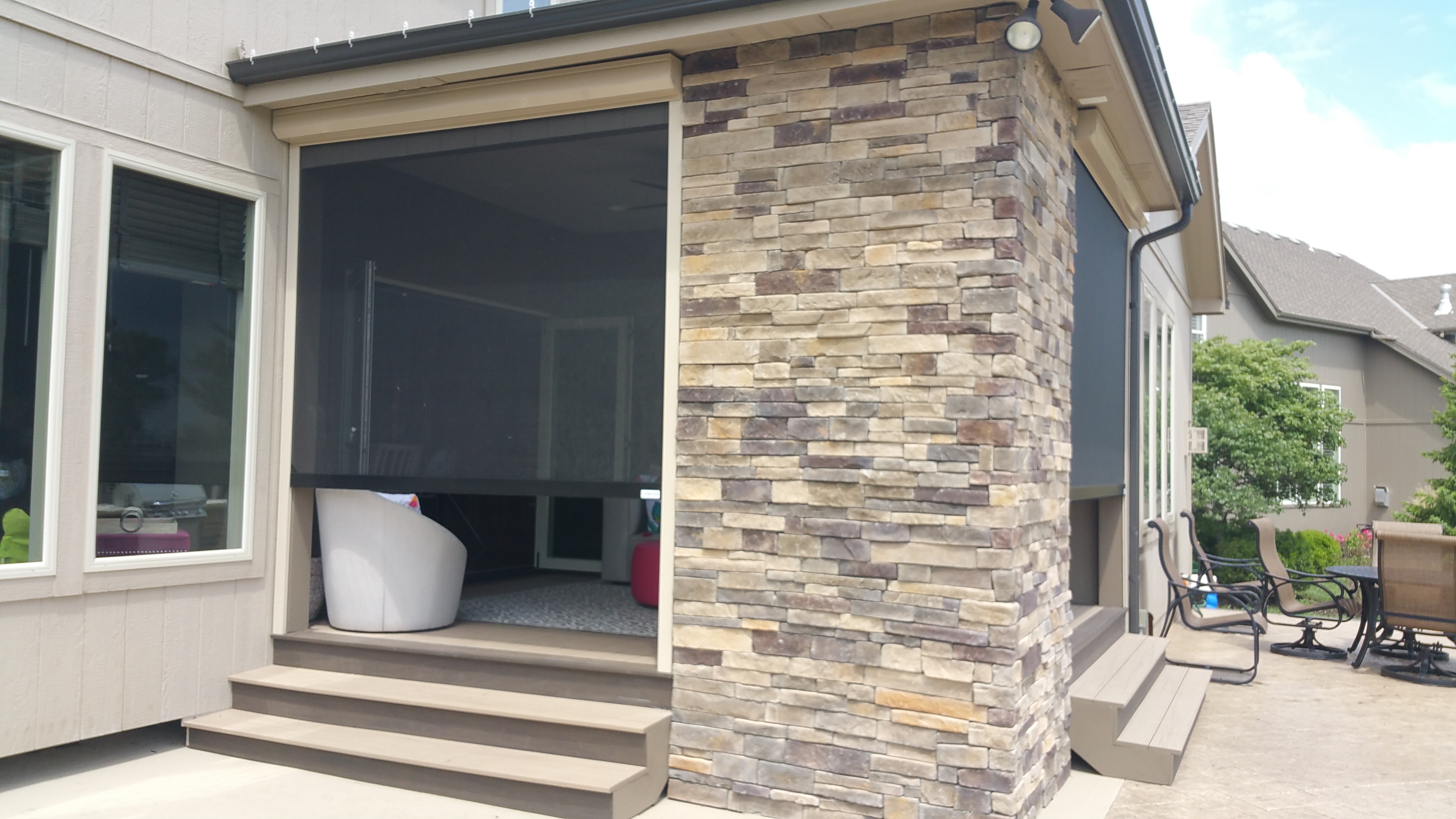 Modern outdoor patio with stone wall and sliding glass door.