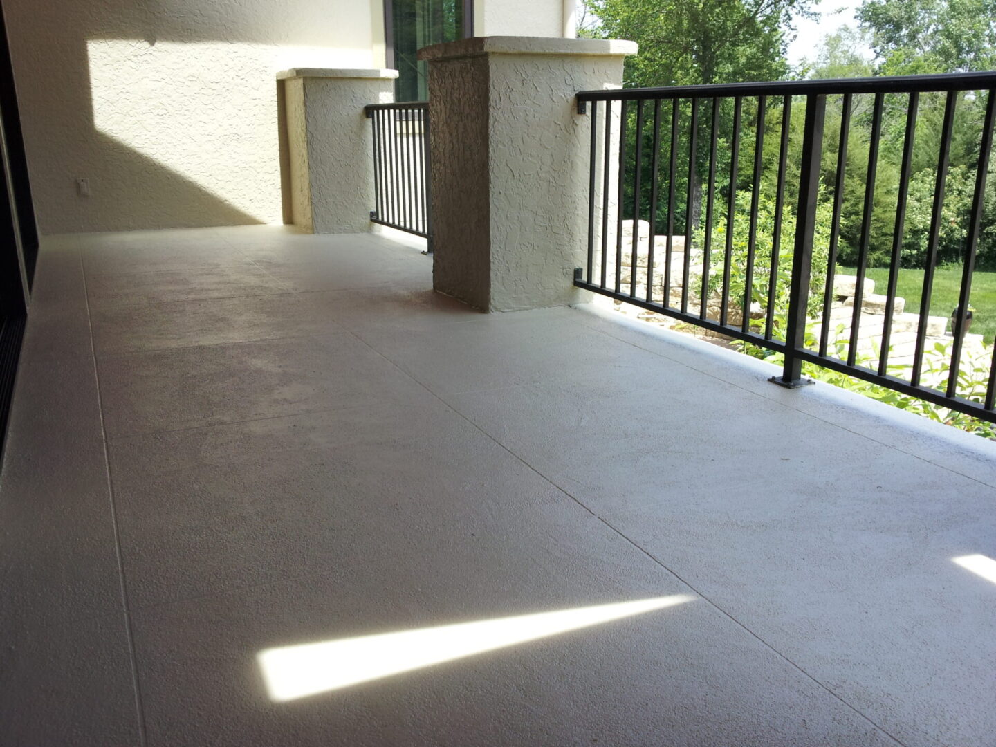 Empty balcony with tiled floor and metal railing overlooking greenery.