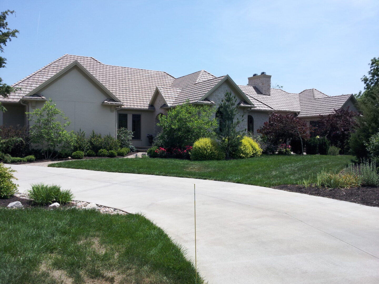 A modern single-story house with a curved driveway and well-kept lawn.
