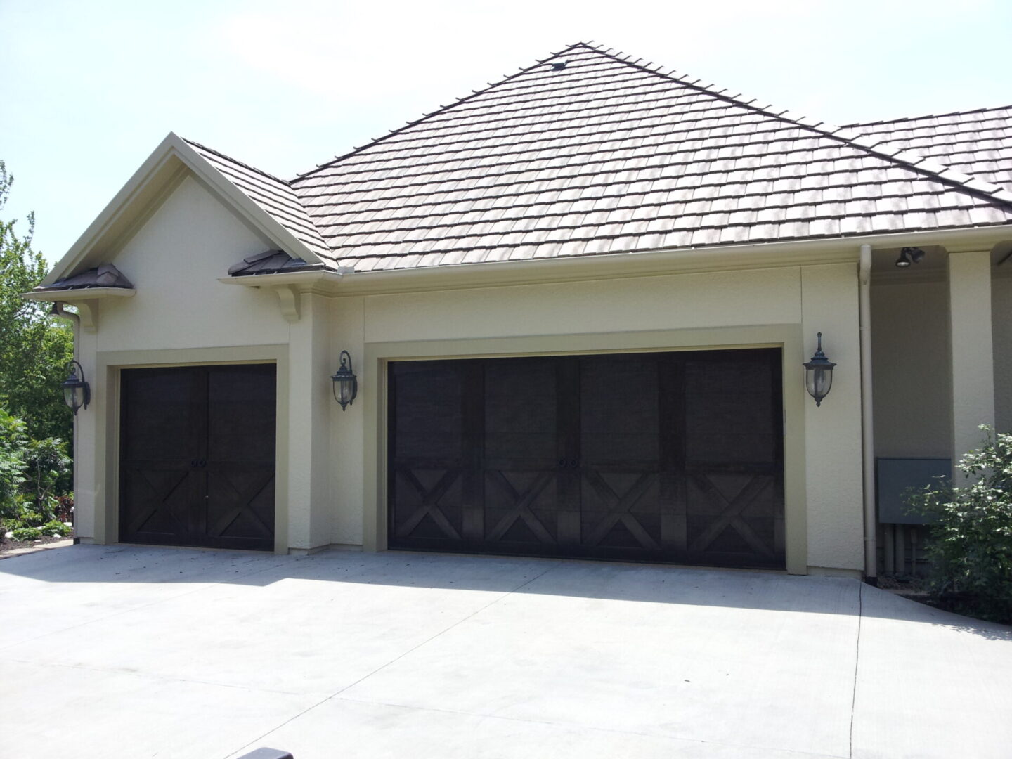 A house with two black garage doors and a light-colored exterior.
