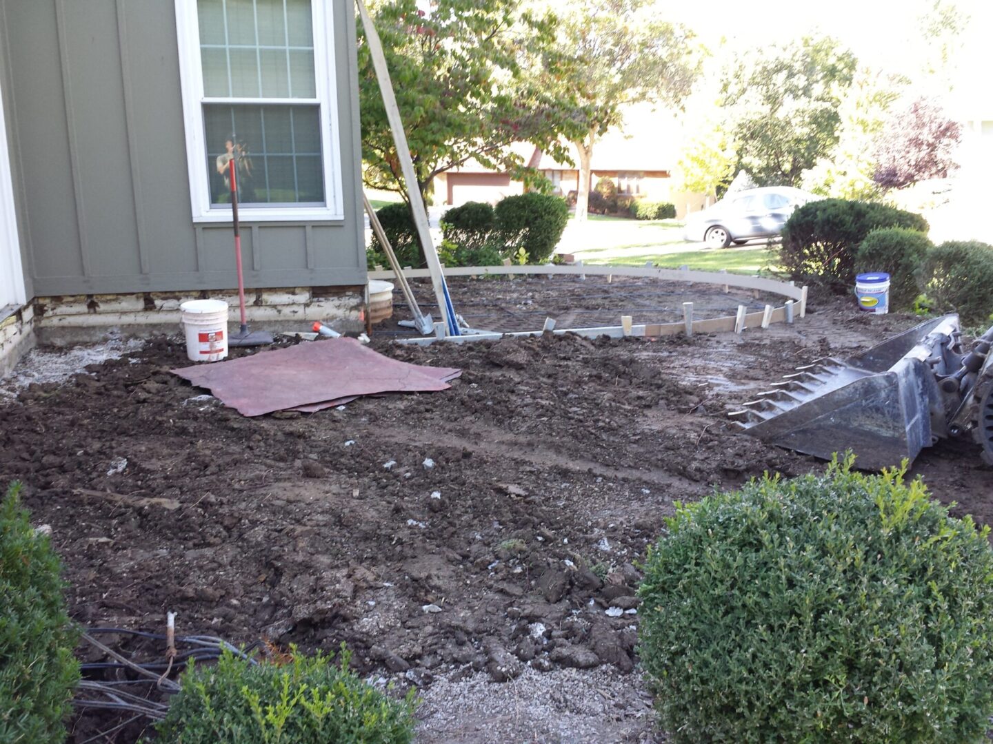 Yard under renovation with soil exposed and tools scattered.