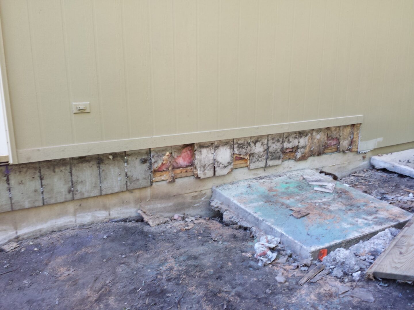Damaged wall with exposed bricks and debris on the floor.