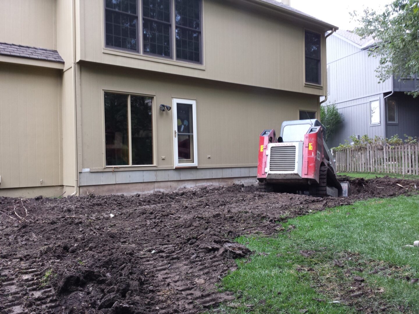 A construction site with a bulldozer near a house preparing the ground.