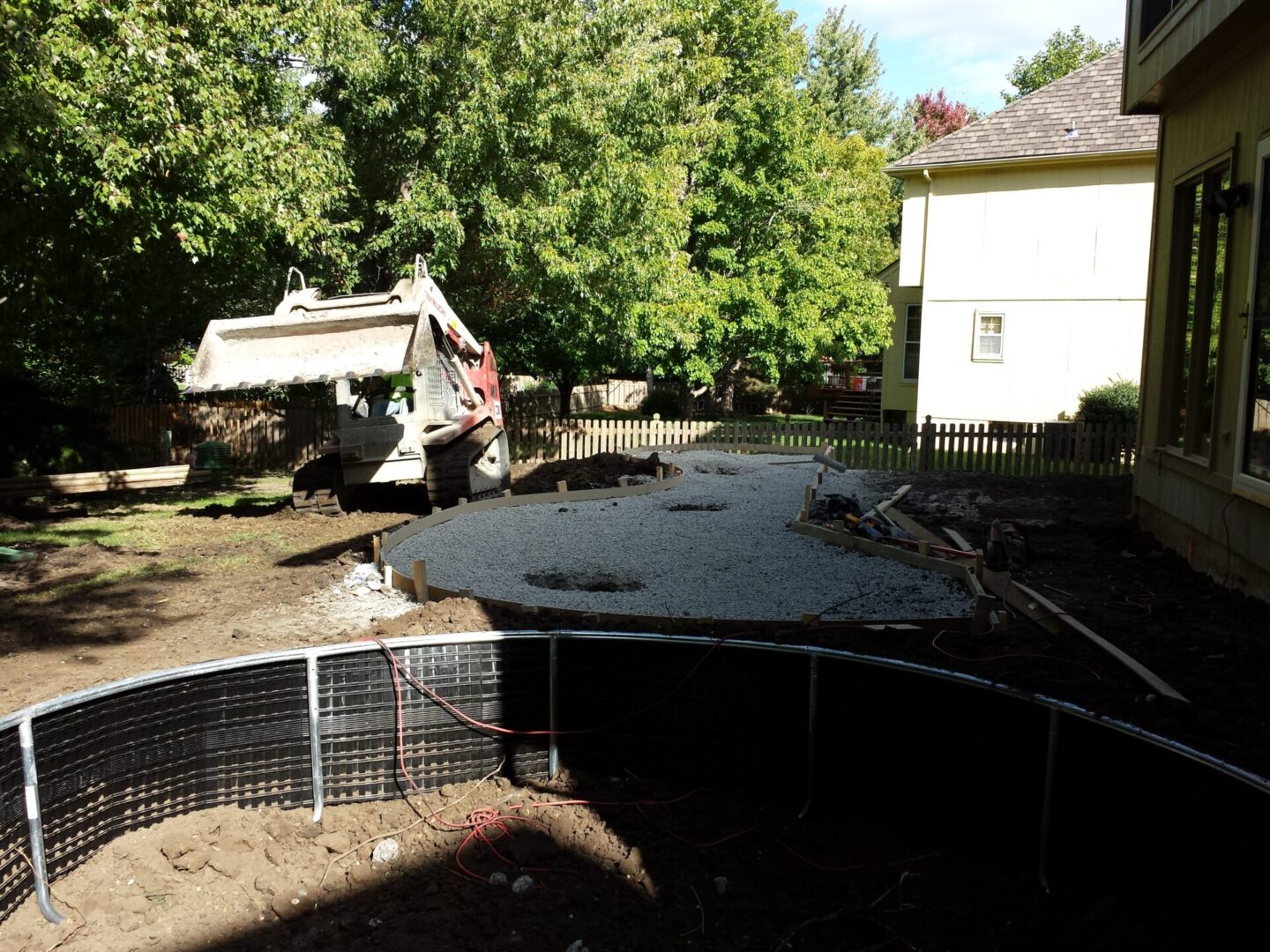 Fresh concrete being poured in a backyard construction site.
