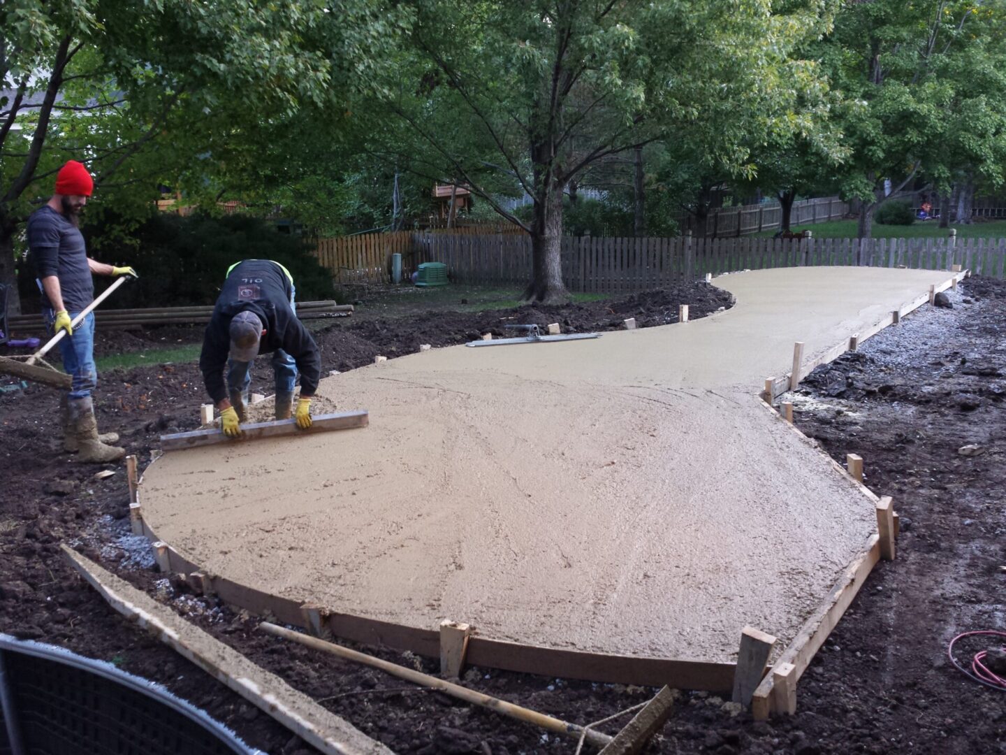 Workers smoothing freshly poured concrete on a patio.