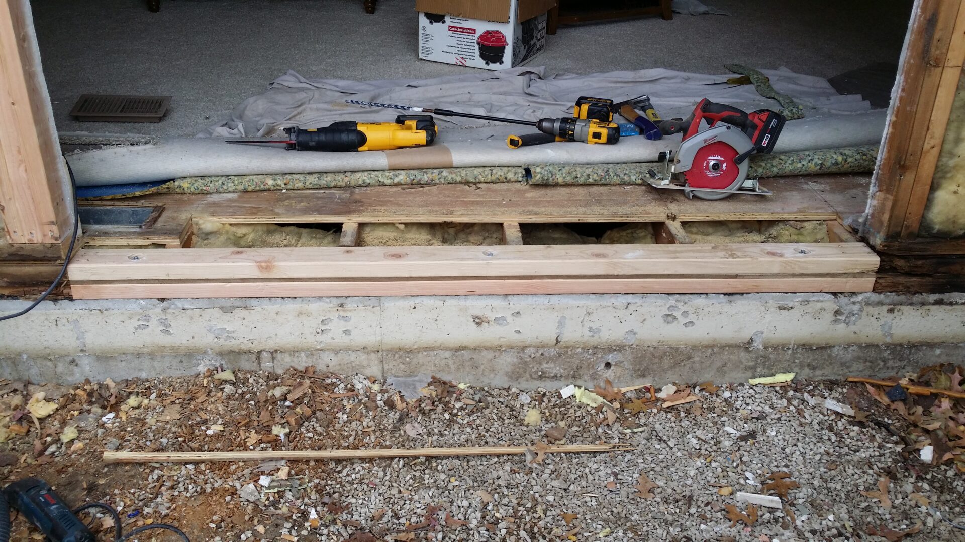 Wooden planks and tools on a construction site floor with an open floor section.