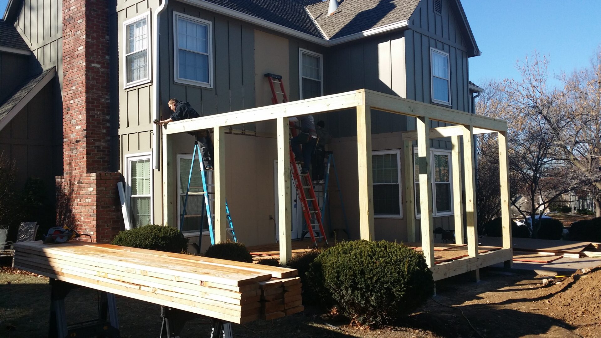 Construction of a wooden sunroom extension on a house.