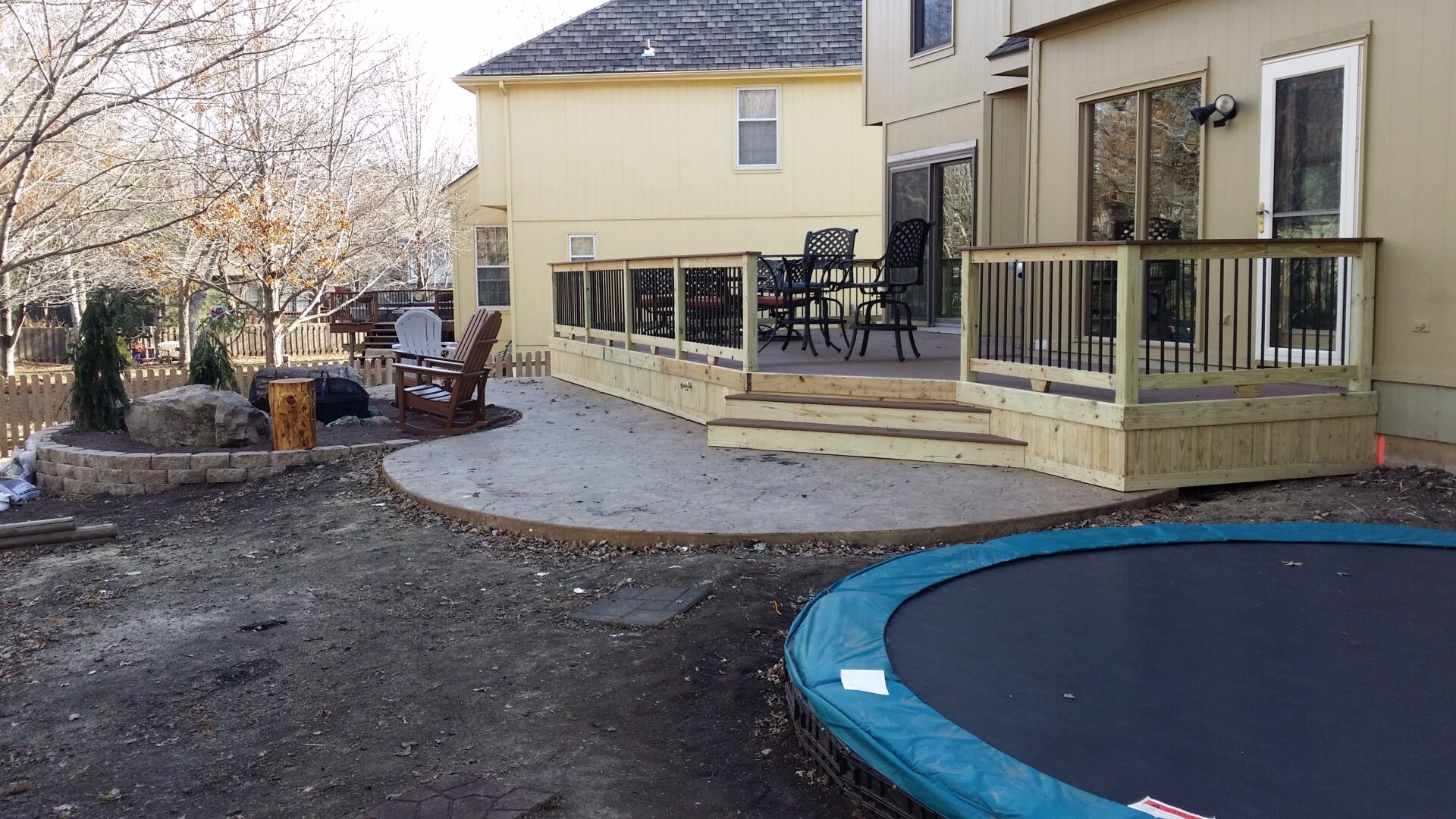 Backyard patio with raised deck and trampoline area.