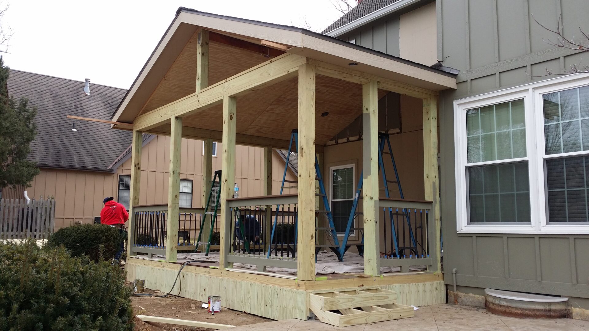 Wooden porch structure under construction beside a house.