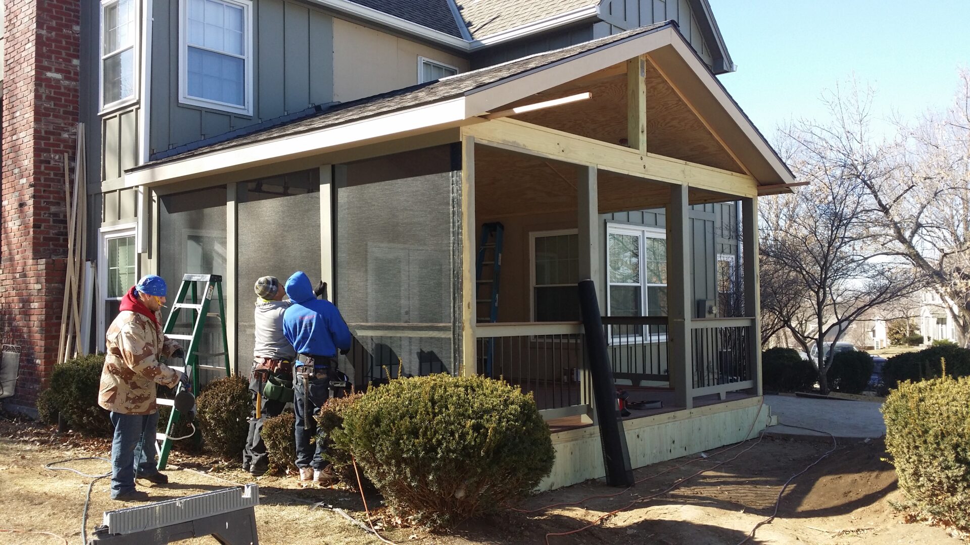Workers installing screens on a patio enclosure.