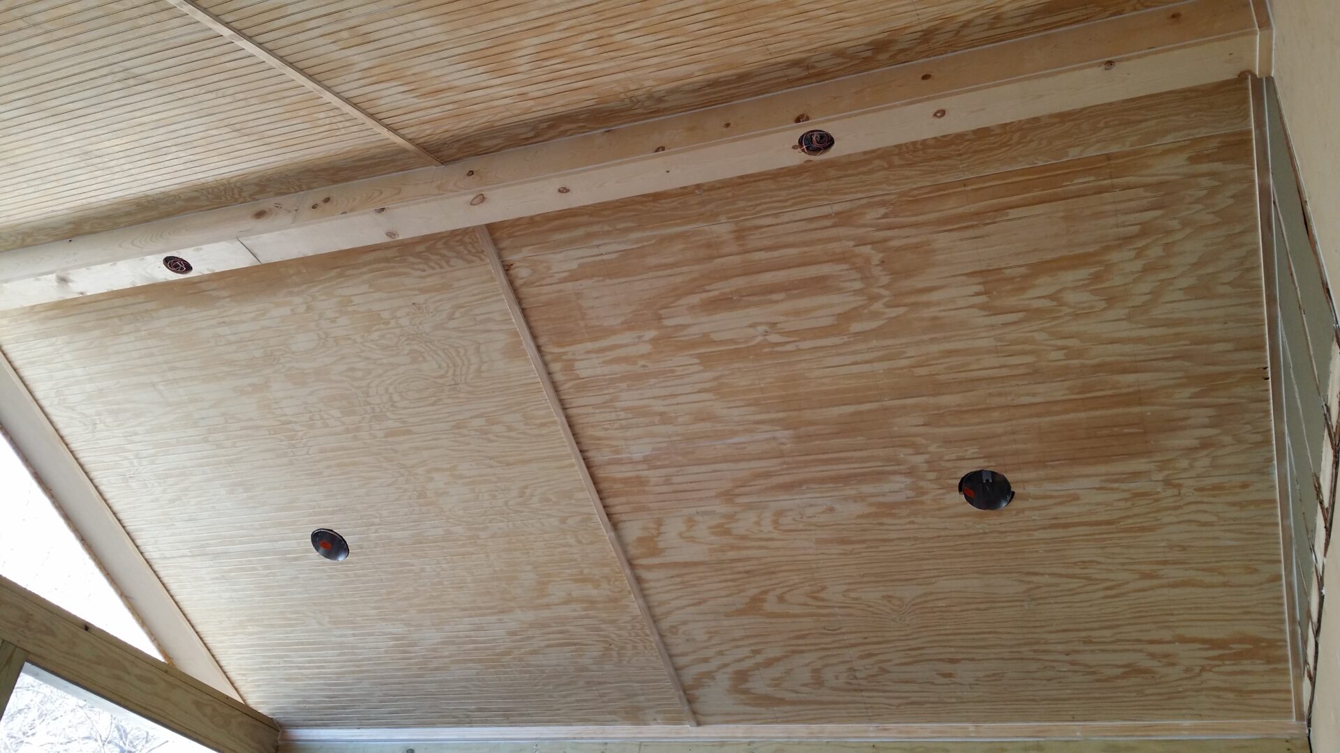 Plywood ceiling with circular cutouts and wooden beams.