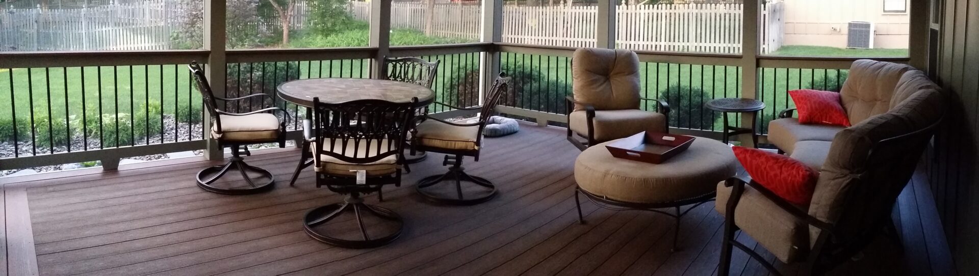 Cozy porch seating with cushioned chairs and a round table on a wooden deck.