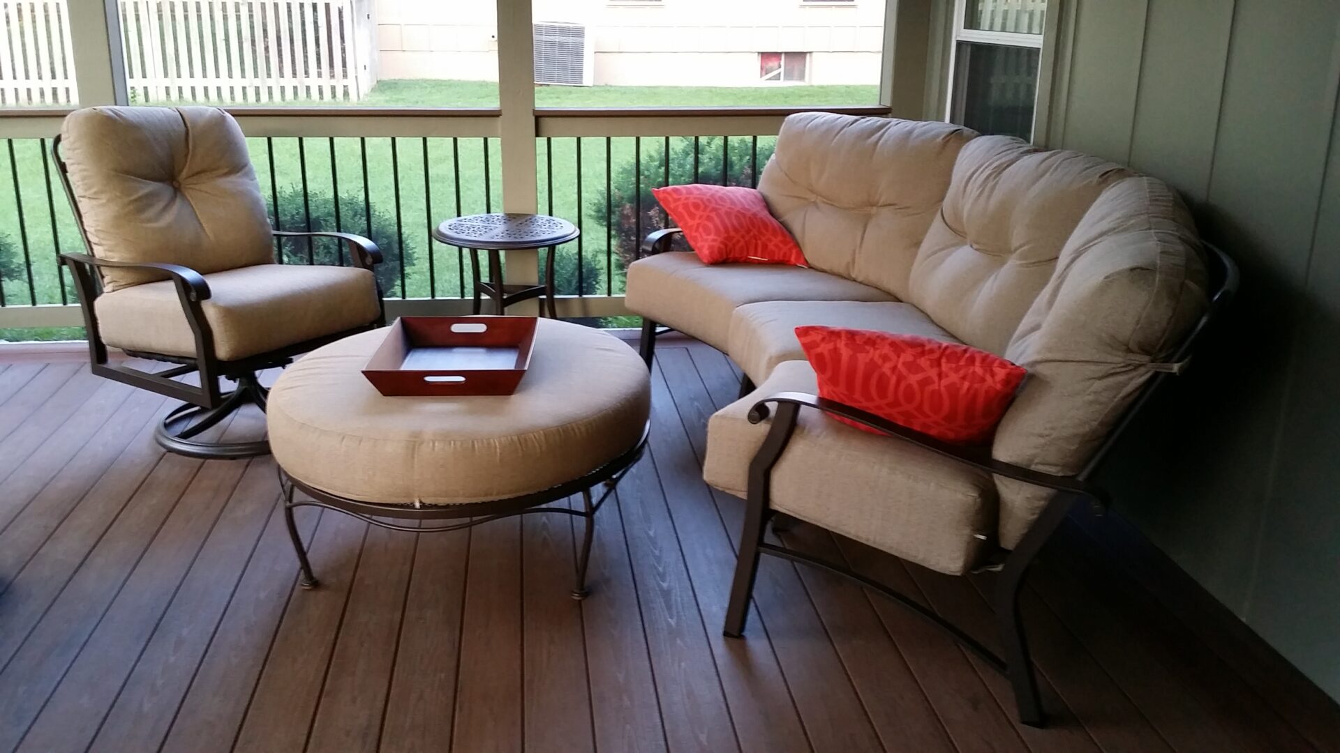 Cozy outdoor seating with cushioned chairs and a round ottoman on a wooden deck.