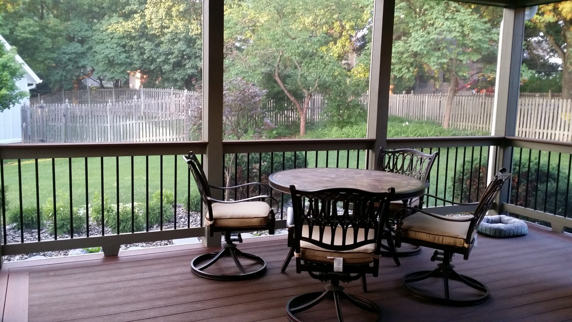 Cozy outdoor patio with a round table and swivel chairs overlooking a green backyard.