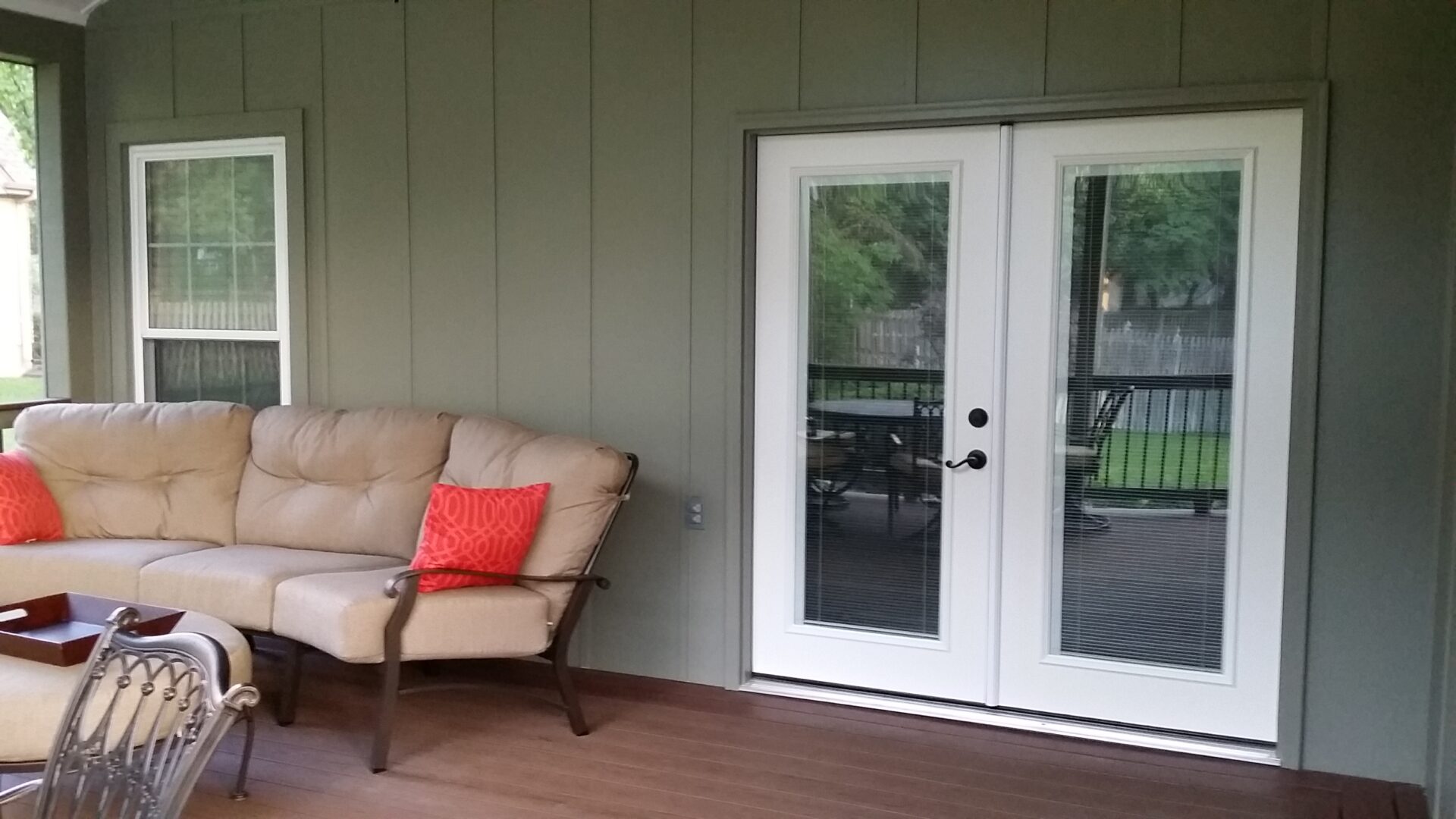 Cozy porch area with cushioned bench and glass double doors.