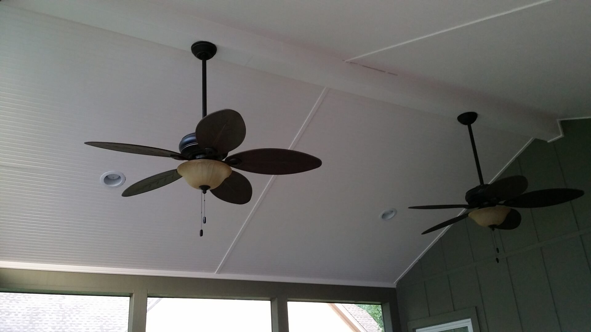 Ceiling fans with dark blades mounted on a white ceiling.