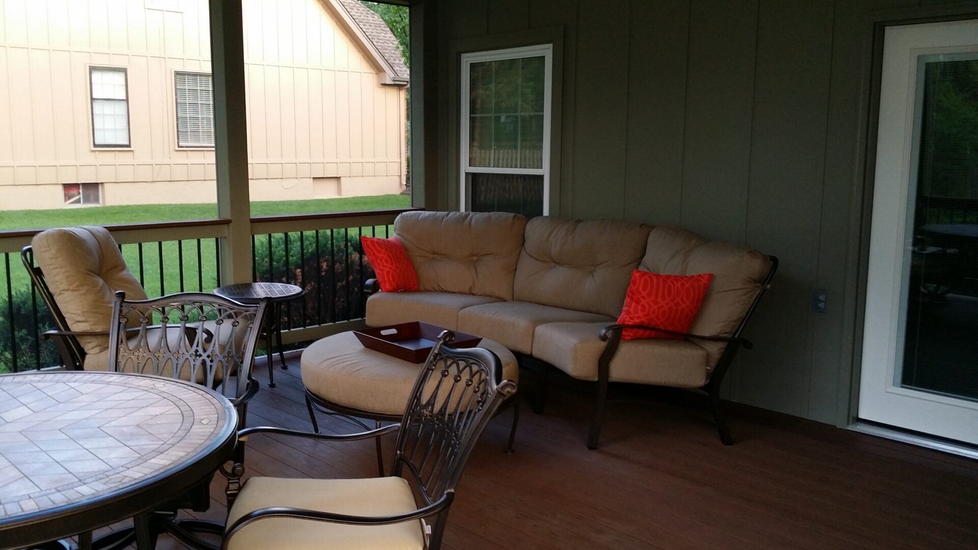 Cozy outdoor seating area with cushioned sofa and chairs on a wooden porch.