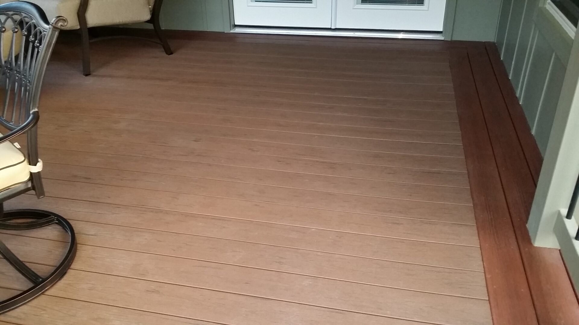 Empty wooden deck floor outside a glass door.