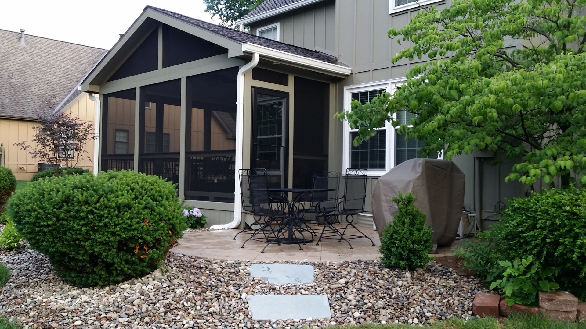Outdoor patio with metal furniture and screened porch.