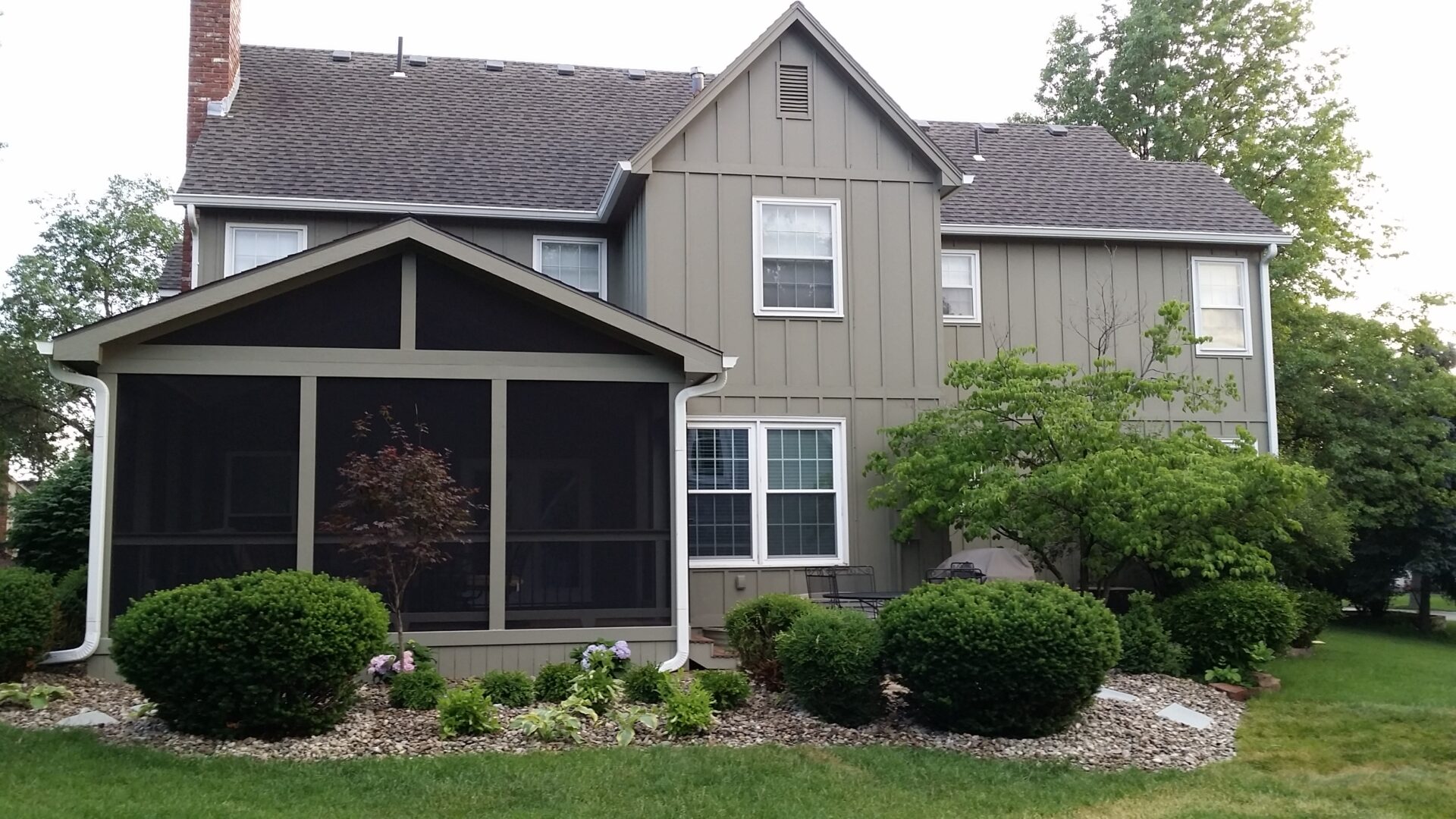 Suburban house with screened porch and landscaped garden.