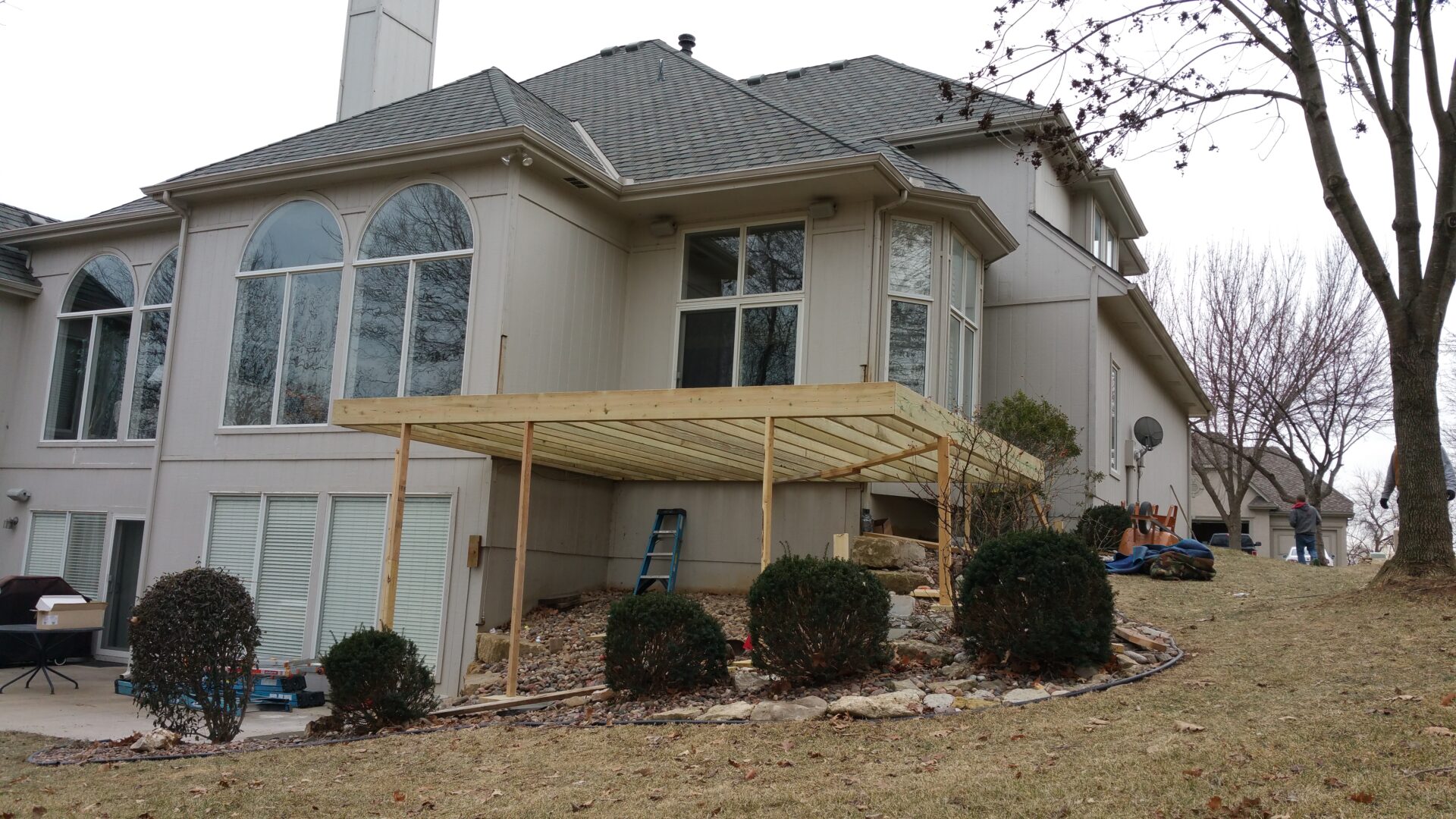 Two-story house with a wooden pergola and large windows.