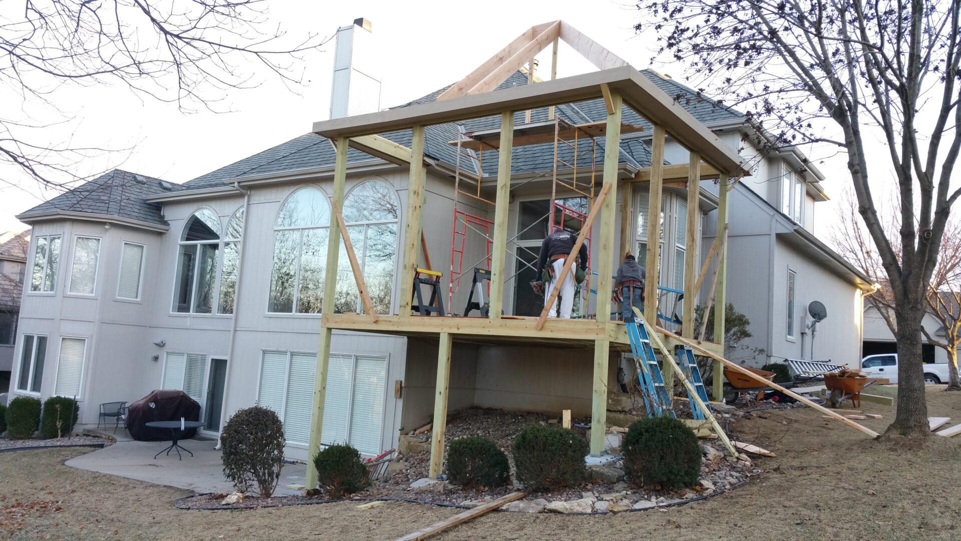 Construction of a wooden deck extension on a house's upper level.