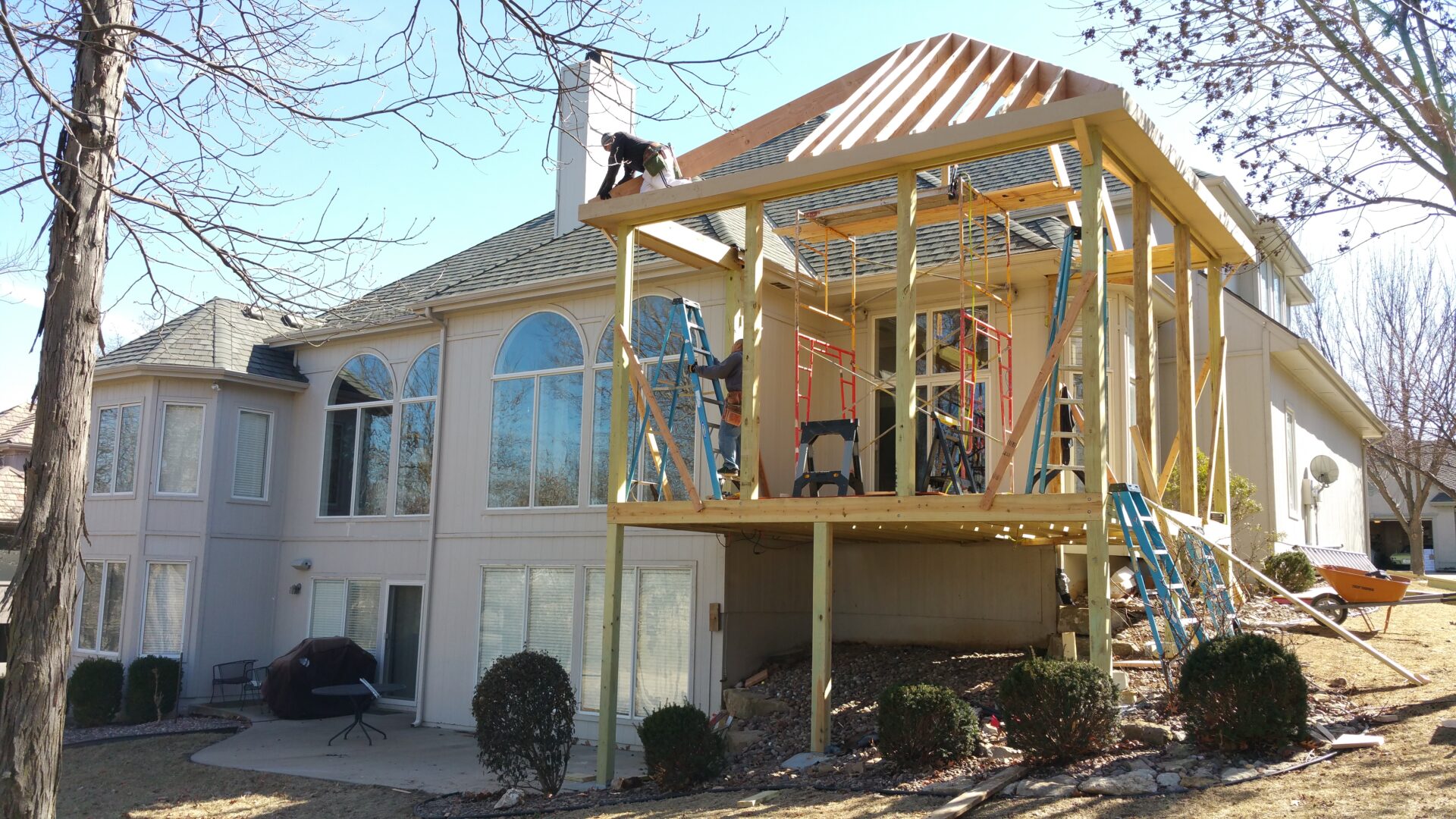 Construction workers building a wooden extension on a house.