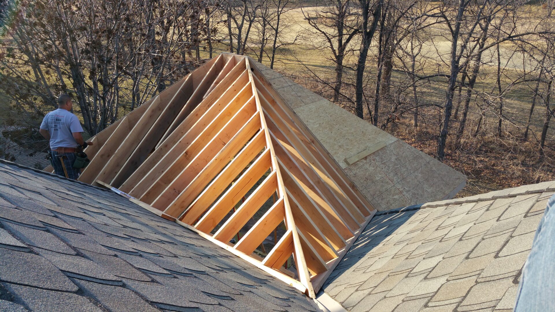 Wooden roof truss structure under construction on a house.