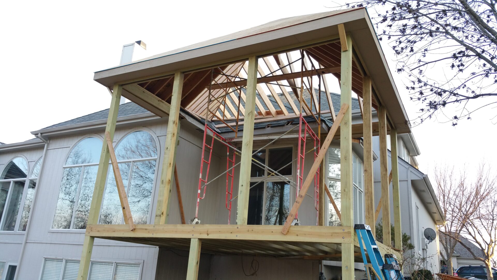 House under construction with exposed framing and scaffolding.