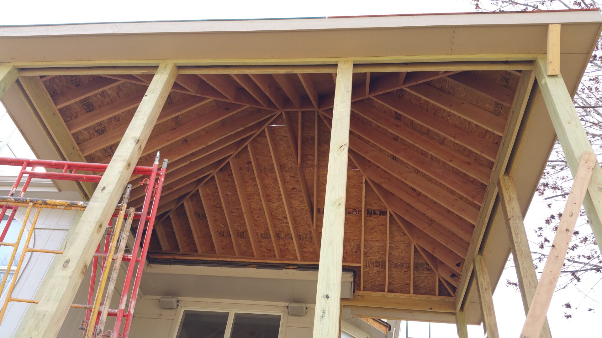 Wooden roof structure under construction with exposed beams.