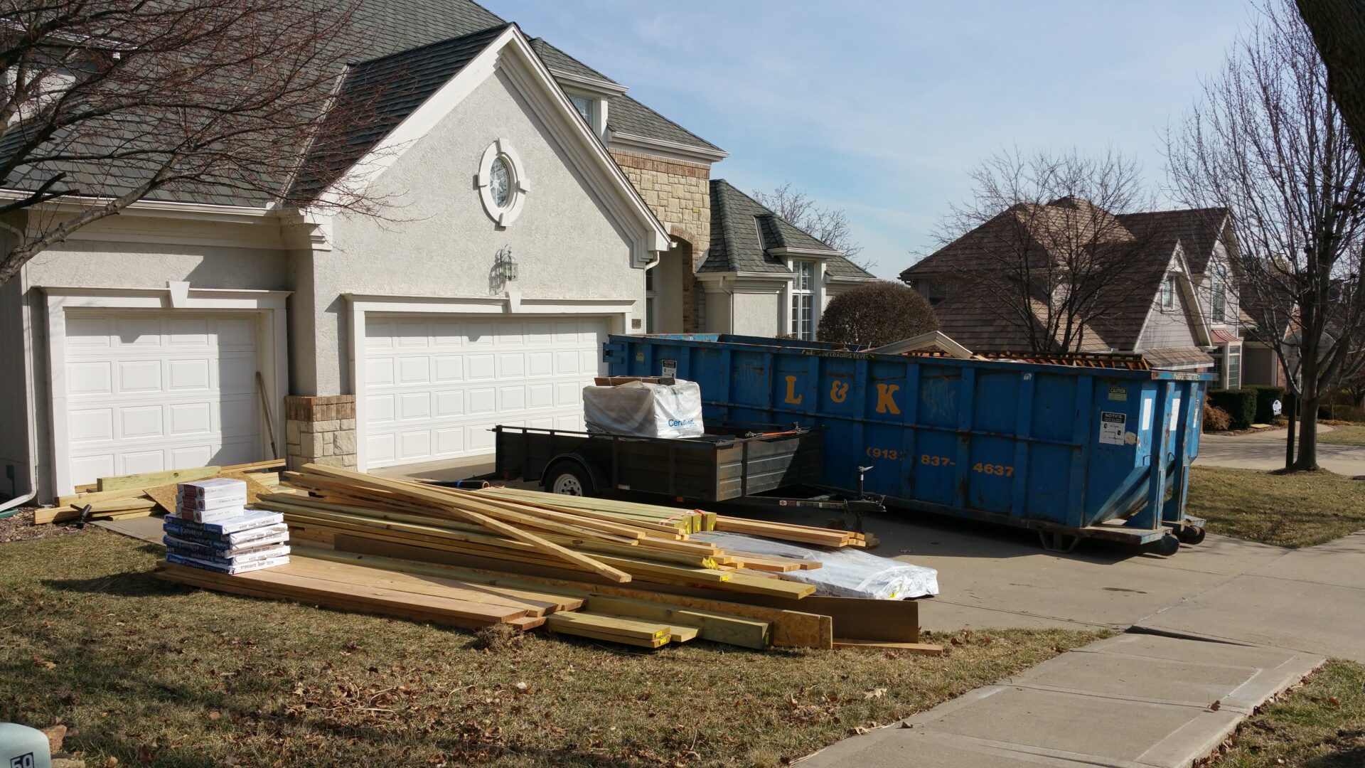 Construction materials and dumpsters outside a suburban home.