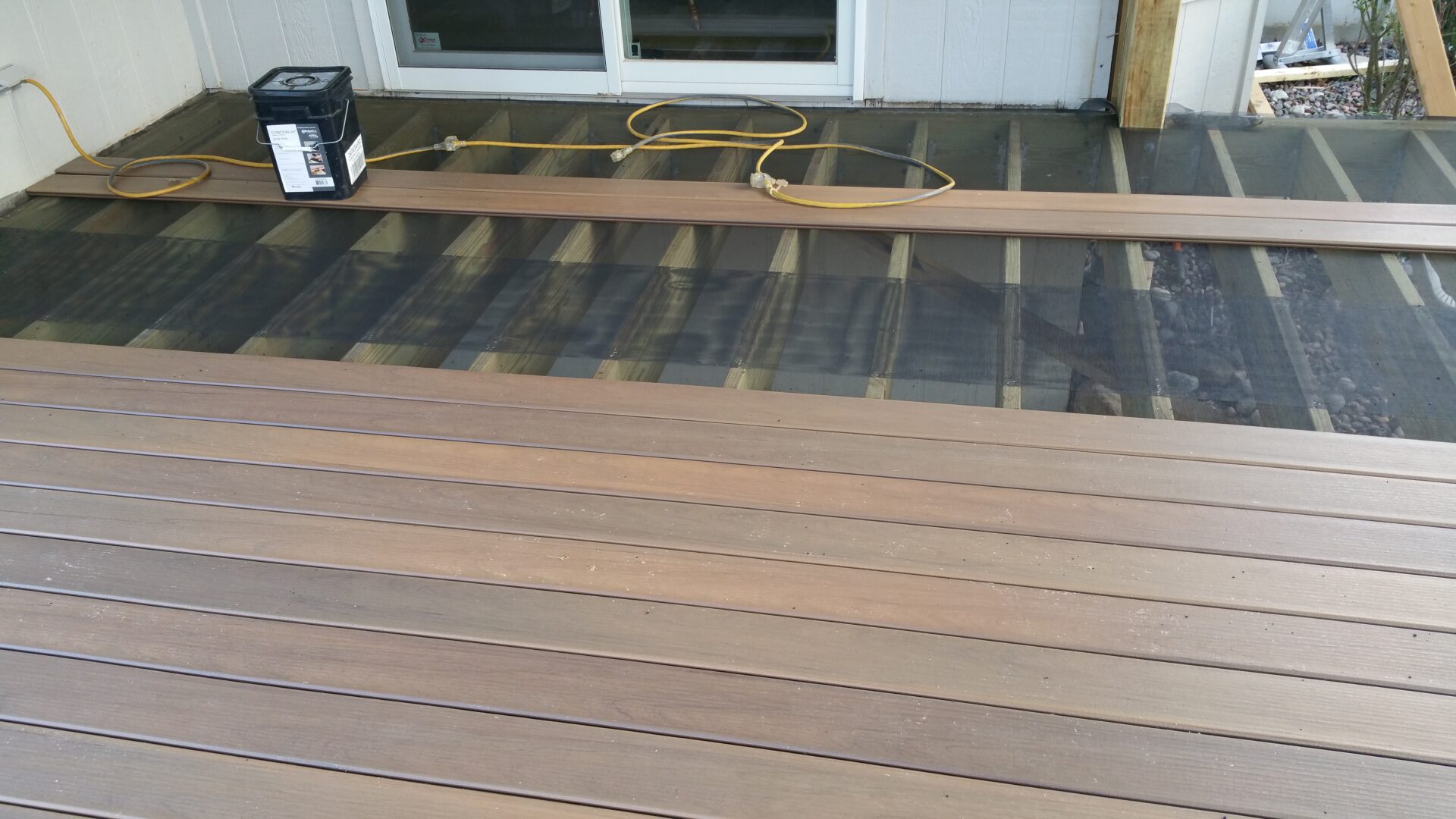 Wooden deck with boards and underlay visible near a doorway.