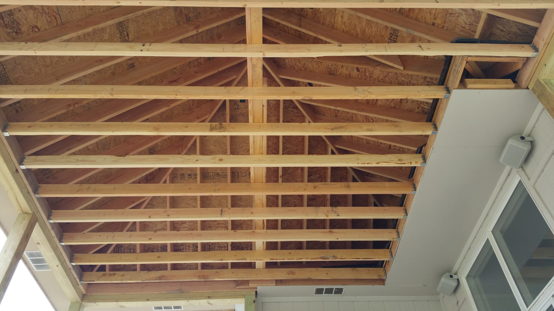 Ceiling with exposed wooden beams and rafters in a building under construction.