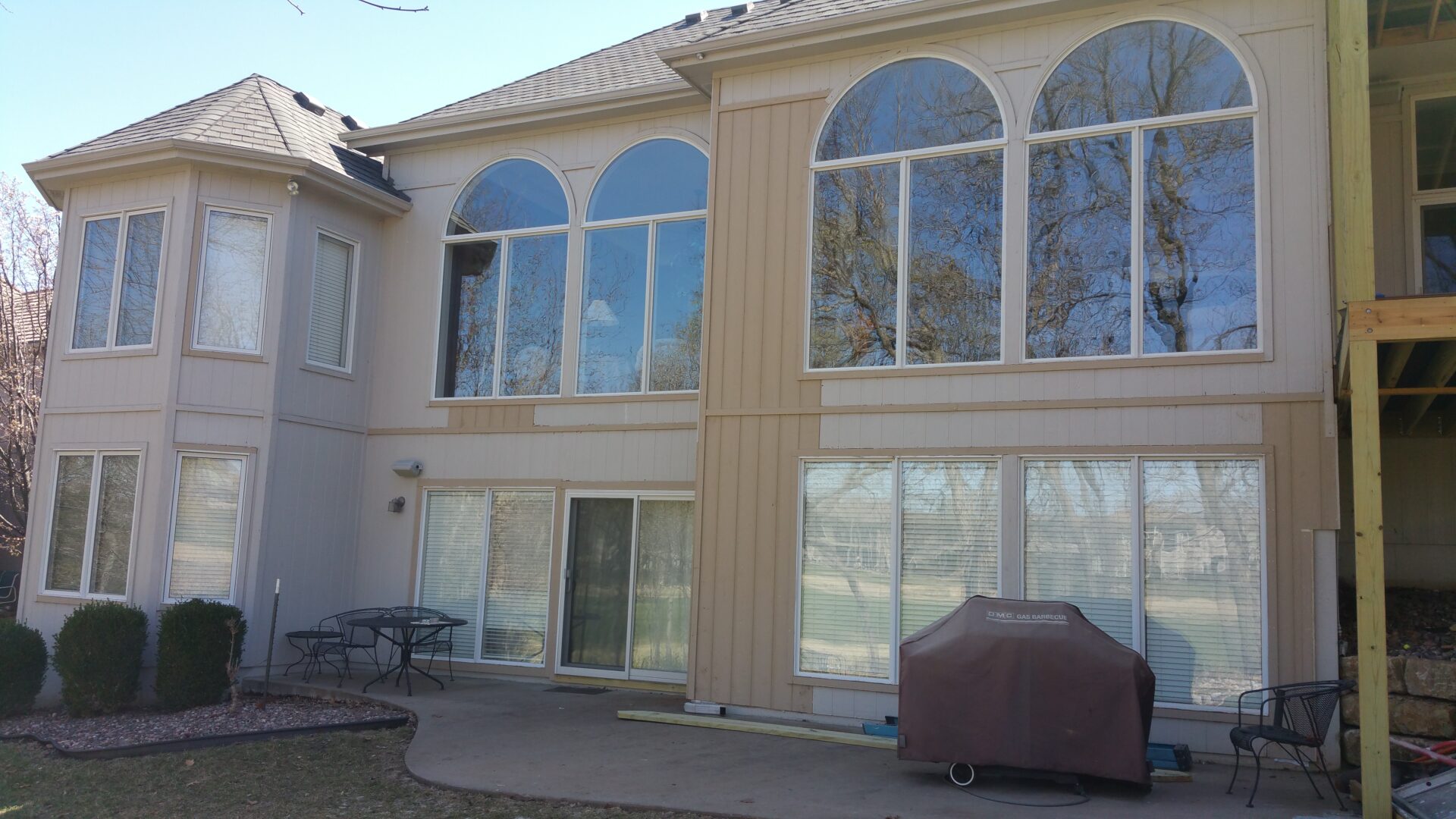 Large house windows with a patio and outdoor grill.