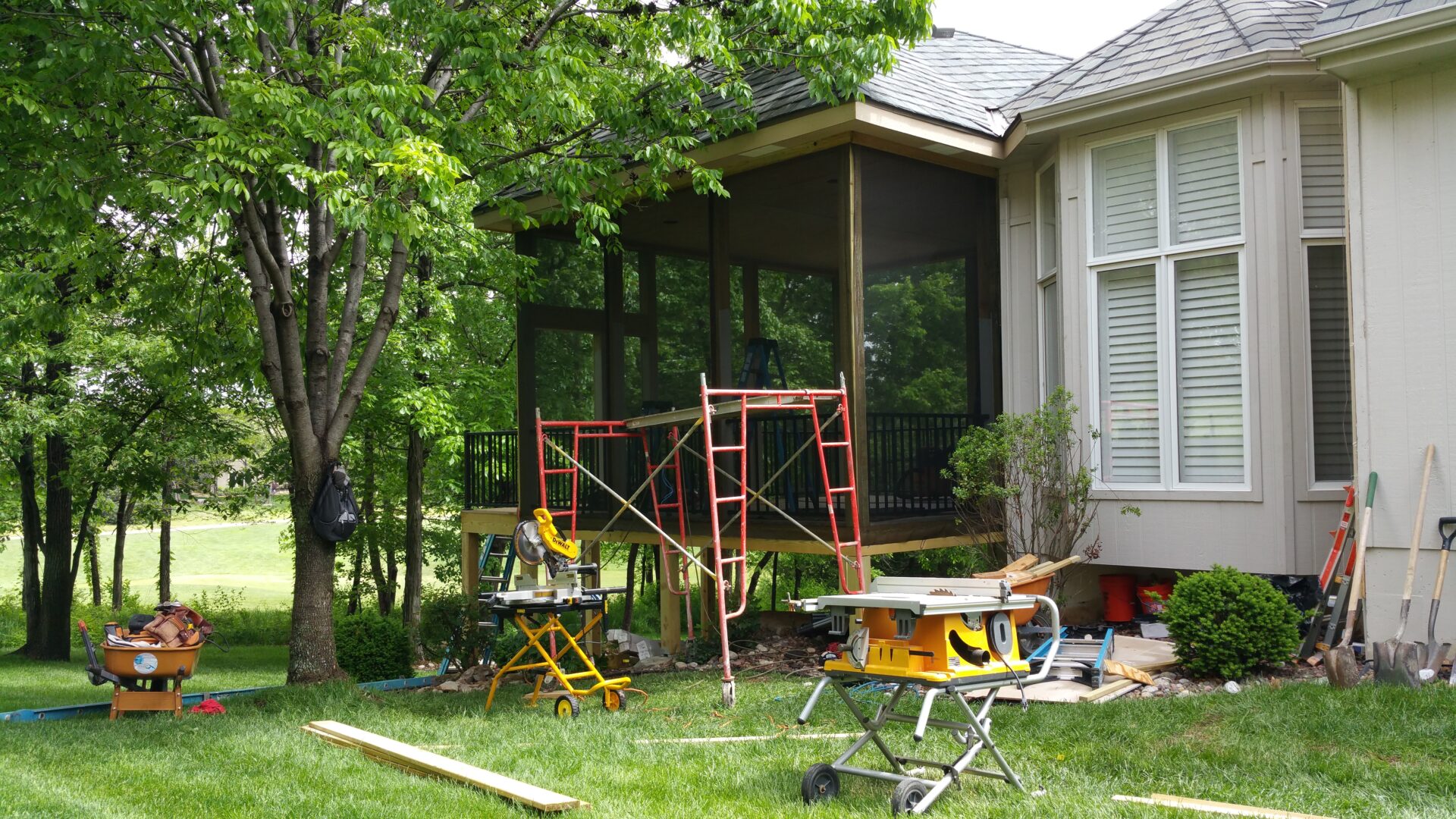 Construction tools and scaffolding set up for a home improvement project on a screened porch.