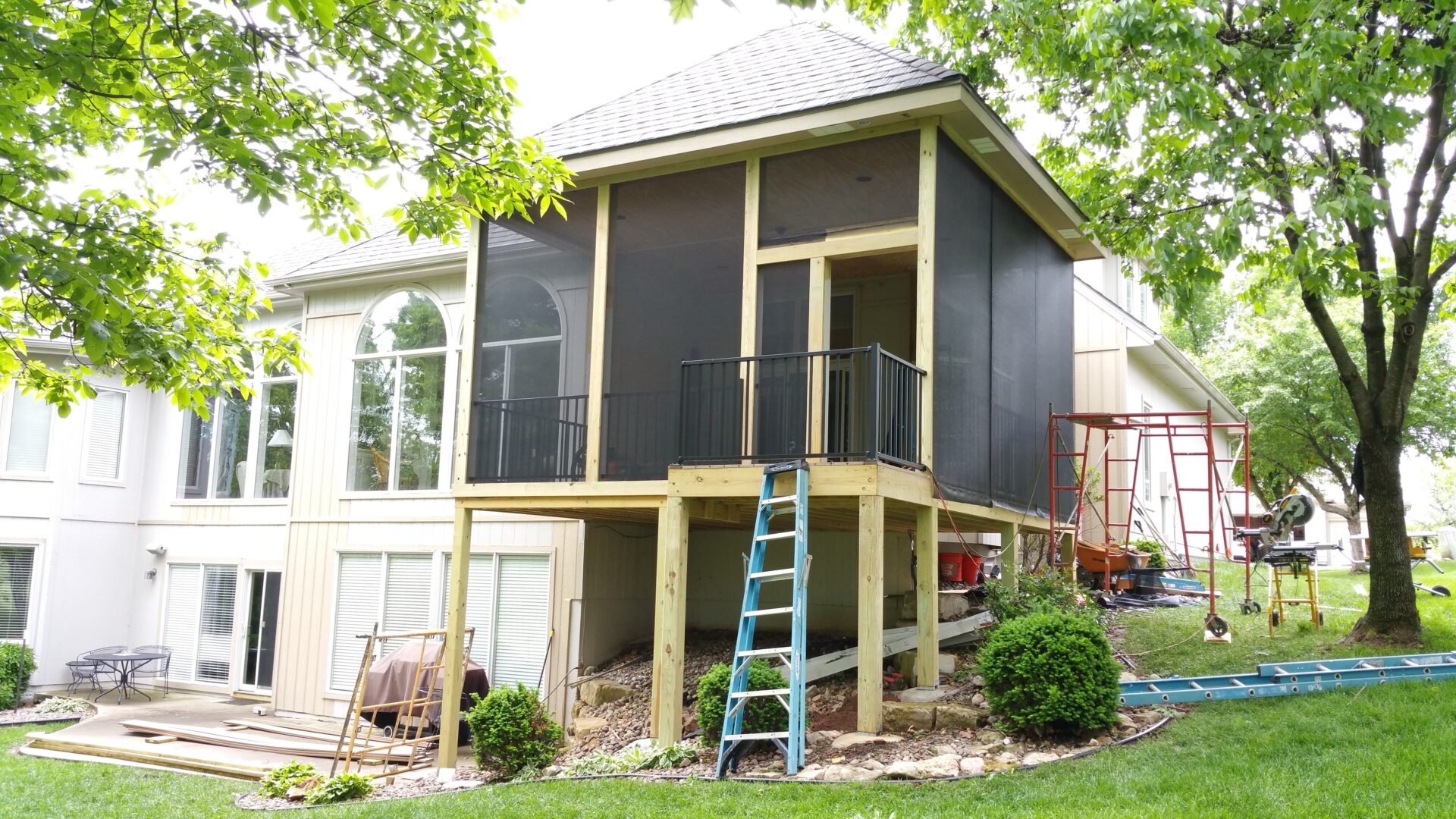 A screened-in porch elevated on stilts attached to a house.