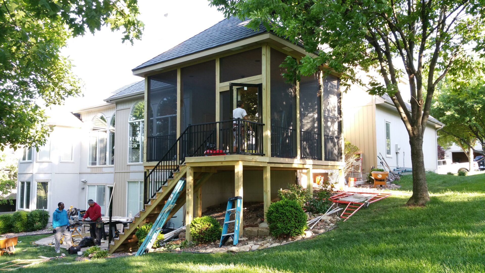 A screened-in porch with outdoor furniture overlooking a green yard.