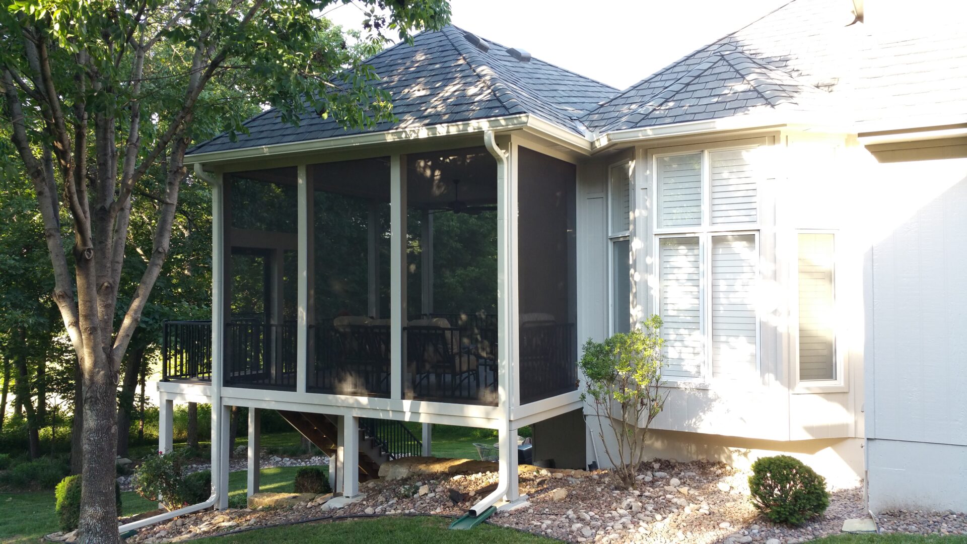 A screened porch attached to a house with white siding.