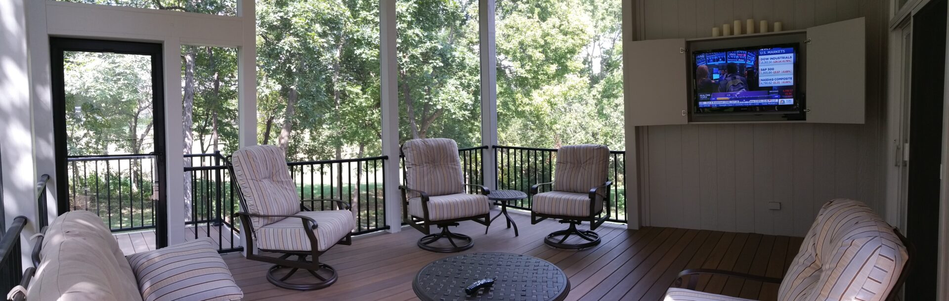 Cozy outdoor seating area with cushioned chairs and a round table on a wooden porch.