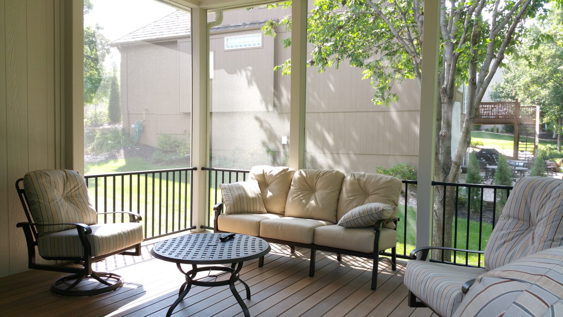Cozy outdoor seating area with cushioned loveseat and round table on a screened porch.