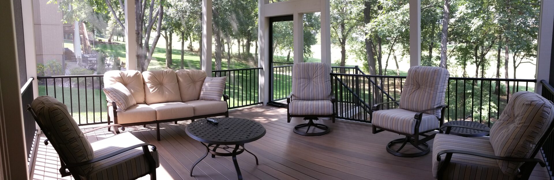 Cozy outdoor seating area on a wooden deck surrounded by greenery.